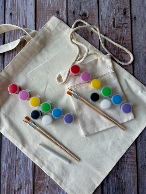 DIY tote painting kit with colorful paints, brushes, and canvas bags on wooden back ground
