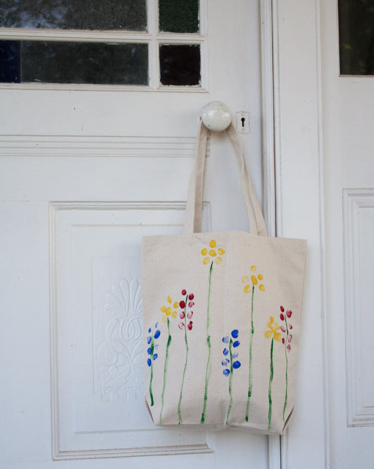 DIY tote painting kit with colorful paints, brushes, and canvas bags on wooden back ground