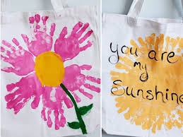 DIY tote painting kit with colorful paints, brushes, and canvas bags on wooden back ground