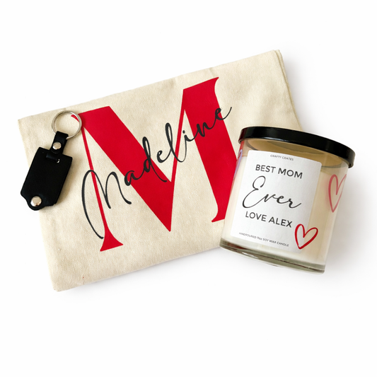 Personalized pouch with red letter 'M' and keychain, alongside a candle labeled 'Best Mom Ever', on a white background.