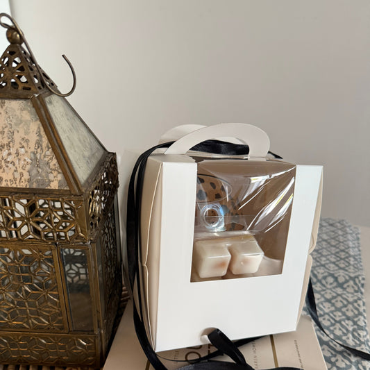 Candle packaging with black ribbon on a textured surface