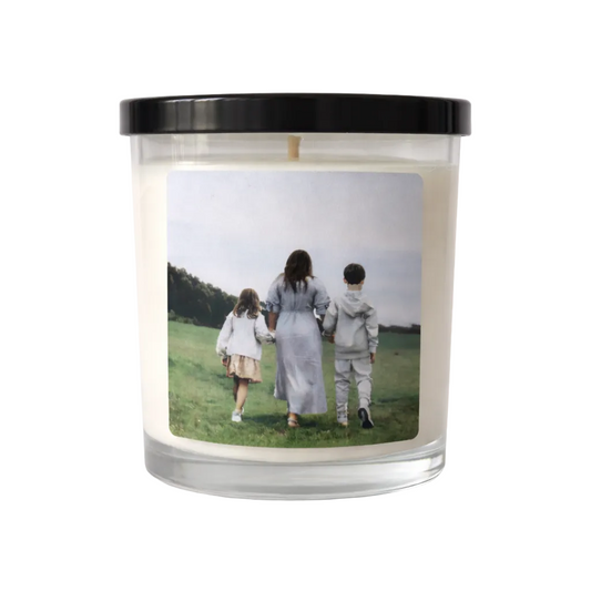 Candle with a printed photo of three people walking on a field on its label.