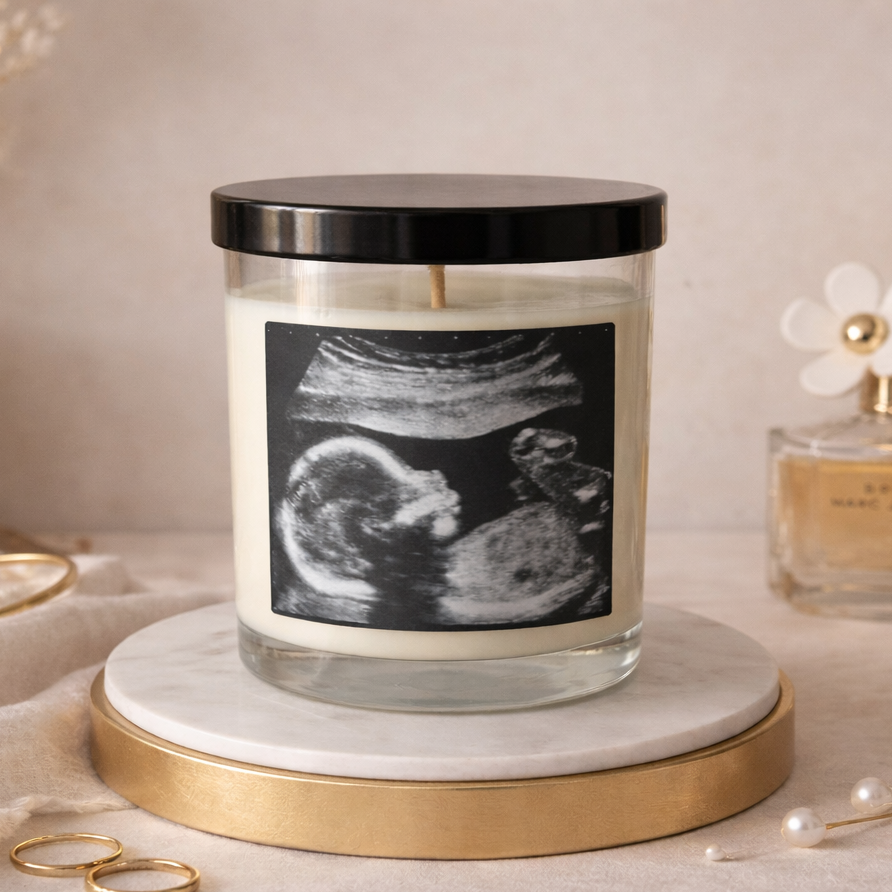 Candle with an ultrasound image on a marble coaster, surrounded by decorative items.