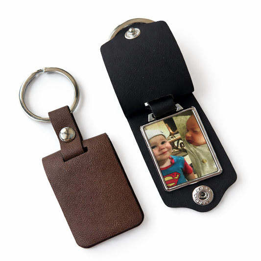 Black and brown leather keychains with photo frame and key ring on a white background