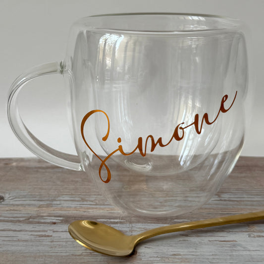 Clear glass mug with gold text on a wooden surface