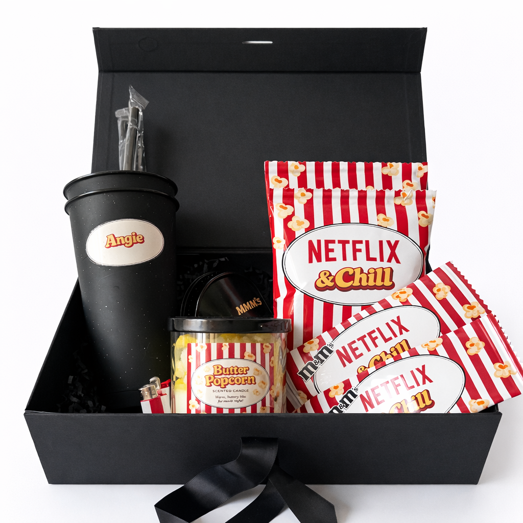Gift set with movie-themed items including a tumbler, popcorn, and snacks in a black box.