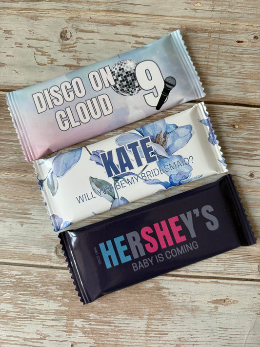 Three Hershey's chocolate bars with personalized wrapping on a wooden surface