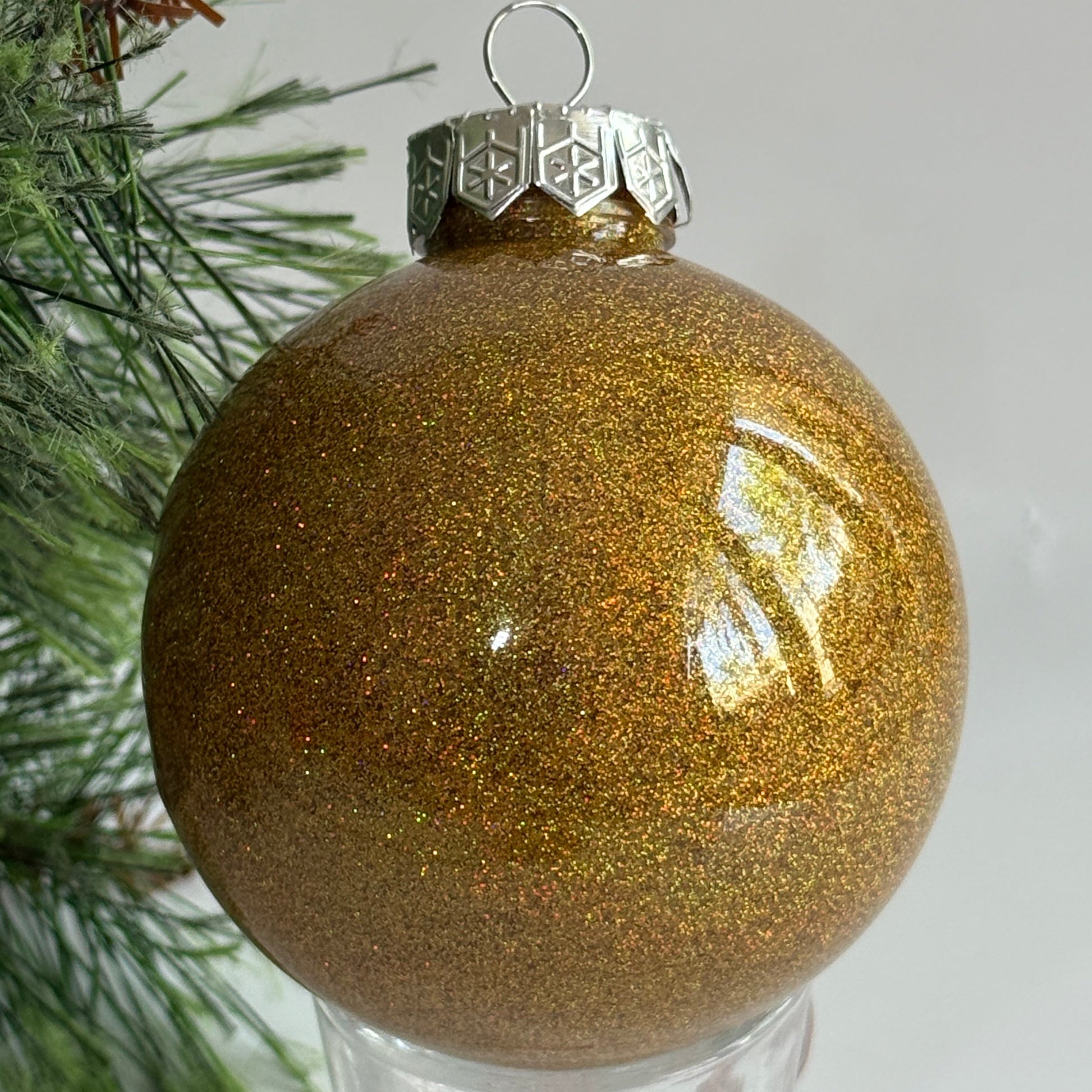 Gold glittery Christmas ornament on a tree branch with a plain background