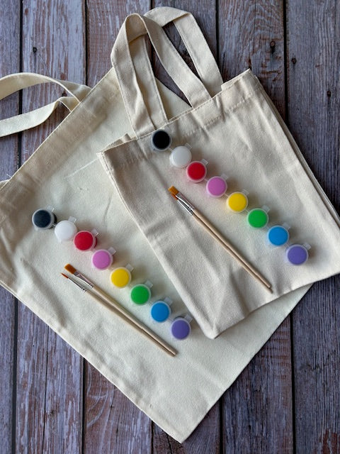 DIY tote painting kit with colorful paints, brushes, and canvas bags on wooden back ground