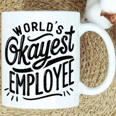 White mug with 'World's Okayest Employee' text on a textured surface